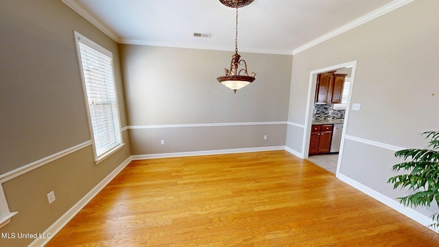 spare room featuring visible vents, light wood-style flooring, baseboards, and ornamental molding