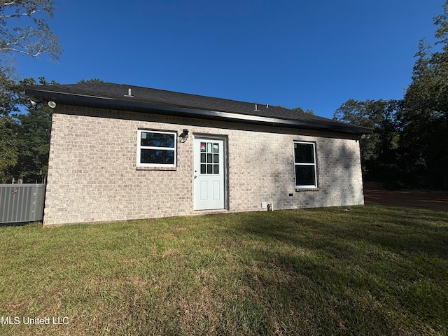 back of property featuring central AC unit and a lawn