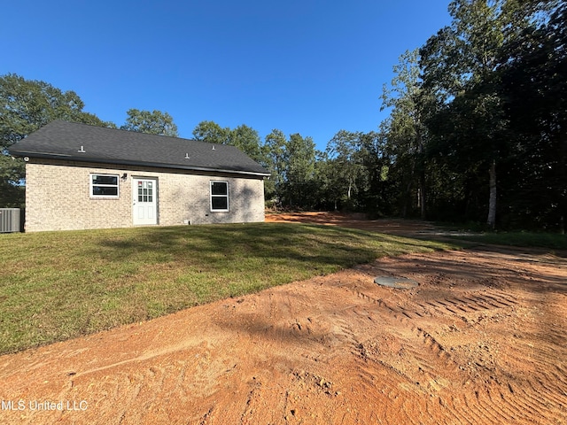 back of property with a yard and central AC