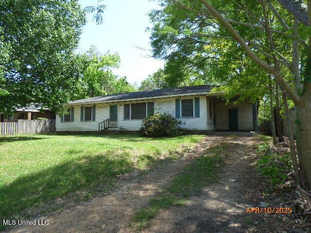 single story home featuring fence, dirt driveway, a carport, and a front lawn