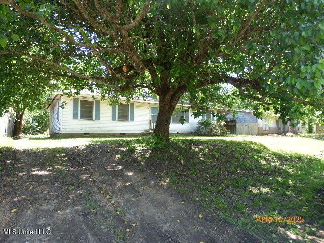 view of property hidden behind natural elements featuring fence and crawl space