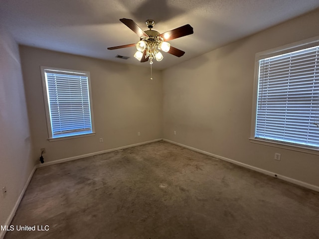 spare room with carpet floors, baseboards, visible vents, and a ceiling fan