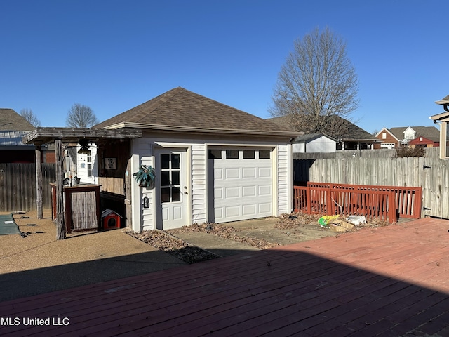 deck with a garage, an outdoor structure, and fence