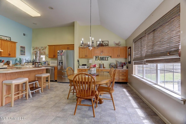dining area with high vaulted ceiling, light tile patterned flooring, an inviting chandelier, baseboards, and visible vents