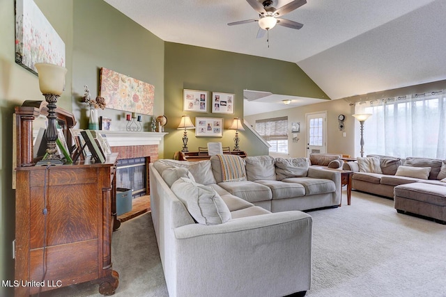 carpeted living area featuring vaulted ceiling, a ceiling fan, and a brick fireplace