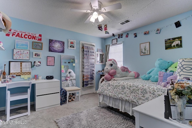 bedroom featuring a ceiling fan, a textured ceiling, visible vents, and carpet