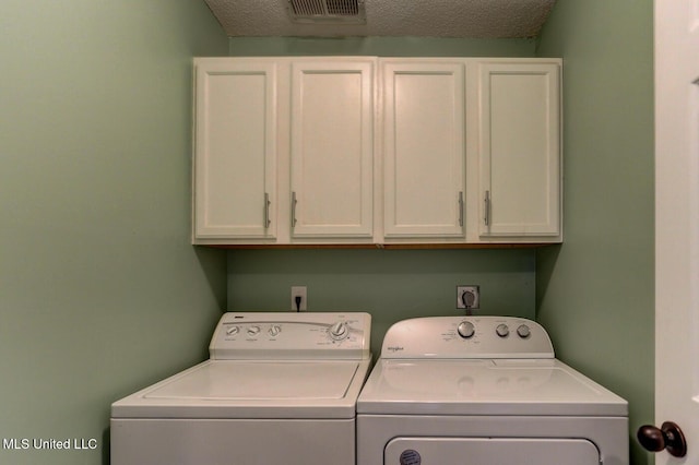 washroom with washer and dryer, cabinet space, a textured ceiling, and visible vents