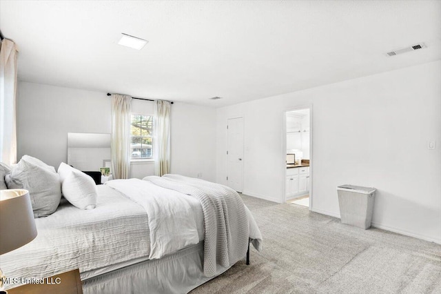 bedroom featuring light carpet and ensuite bathroom