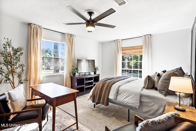 carpeted bedroom featuring a textured ceiling and ceiling fan