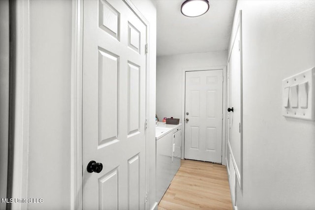 clothes washing area with light hardwood / wood-style flooring and separate washer and dryer