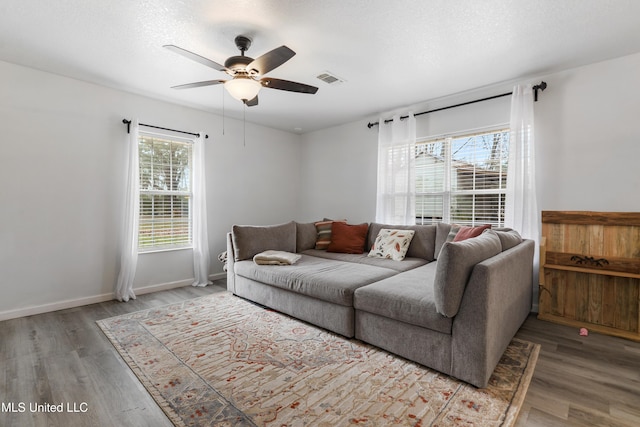 living room featuring ceiling fan, hardwood / wood-style flooring, and a textured ceiling