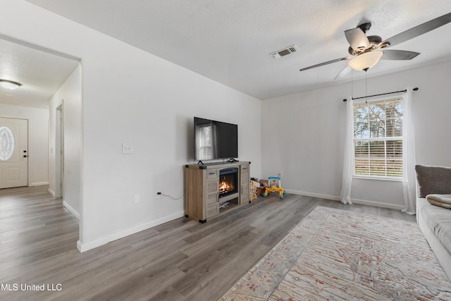 unfurnished living room with ceiling fan, wood-type flooring, and a textured ceiling