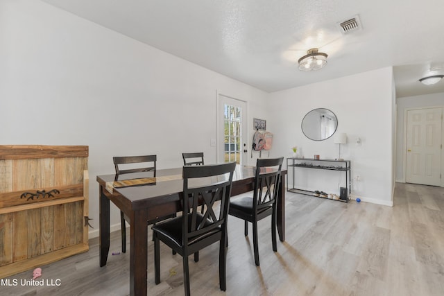 dining space featuring a textured ceiling and light wood-type flooring