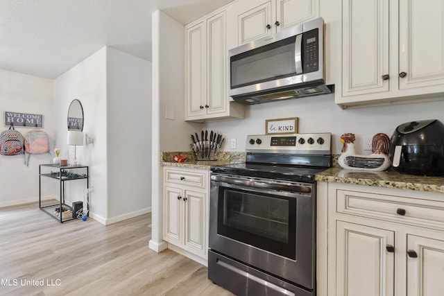 kitchen featuring light stone counters, appliances with stainless steel finishes, and light wood-type flooring