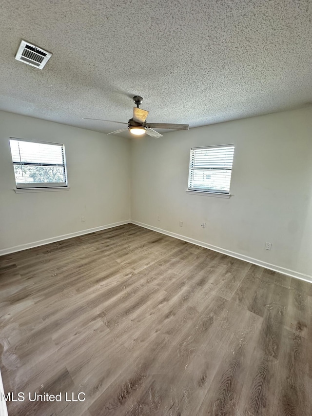 809 Herrick Ave, Pascagoula, MS 39567 - empty room featuring healthy amount of natural light, a textured ceiling, wood finished floors, and a ceiling fan