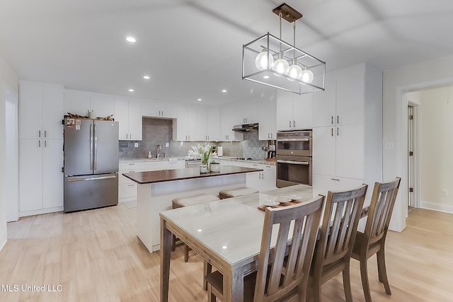 129 Marcie Dr, Long Beach, MS 39560 - kitchen featuring stainless steel appliances, a kitchen island, backsplash, a sink, and light wood-type flooring