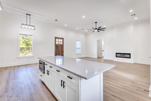 kitchen featuring light hardwood / wood-style floors, a center island, ceiling fan, pendant lighting, and white cabinets