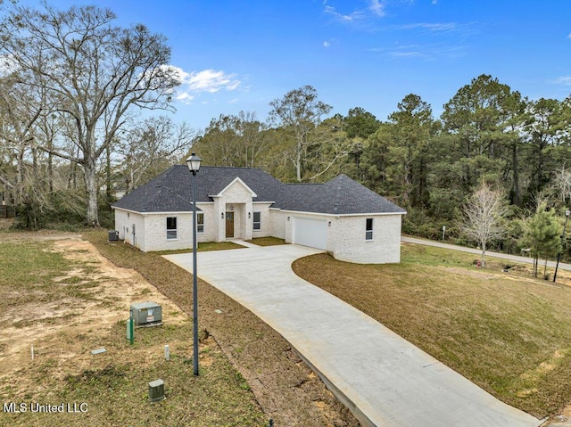 view of front of house featuring a front yard, a garage, and central AC unit