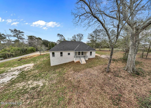 back of property featuring covered porch and a lawn