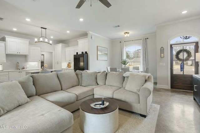 living room featuring crown molding, sink, and ceiling fan with notable chandelier