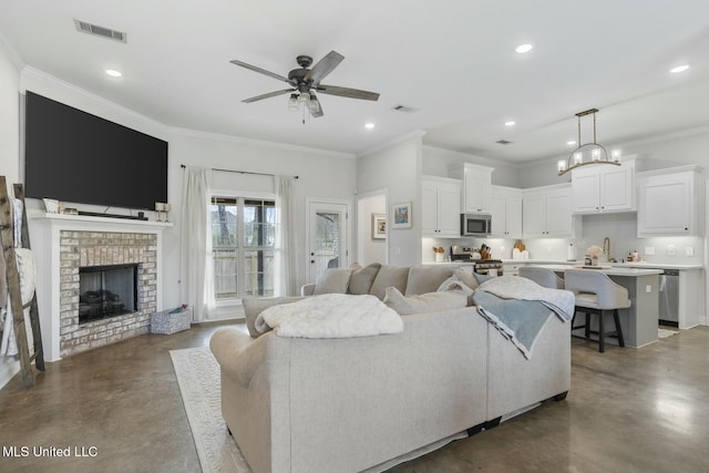 living room with a brick fireplace, ornamental molding, concrete flooring, ceiling fan, and sink