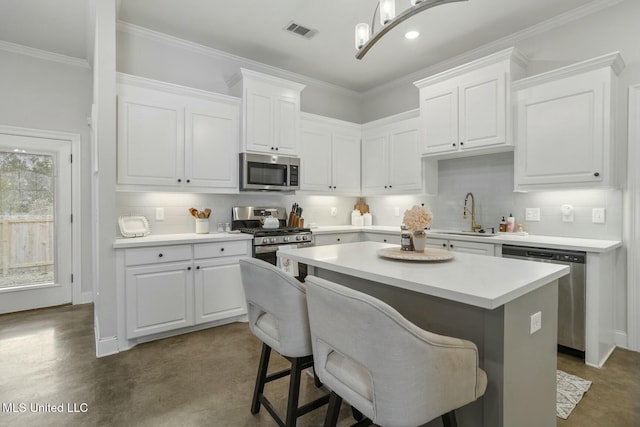 kitchen featuring a kitchen bar, stainless steel appliances, white cabinetry, and sink