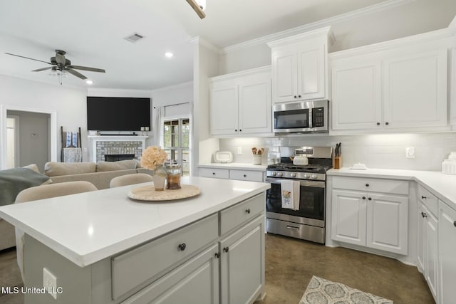 kitchen featuring a center island, white cabinets, decorative backsplash, a fireplace, and appliances with stainless steel finishes