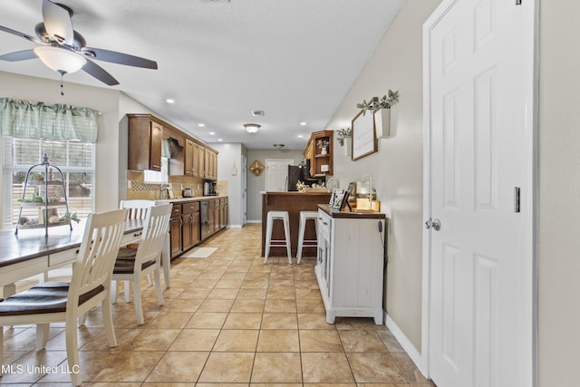 kitchen with light tile patterned floors, backsplash, fridge, a textured ceiling, and kitchen peninsula