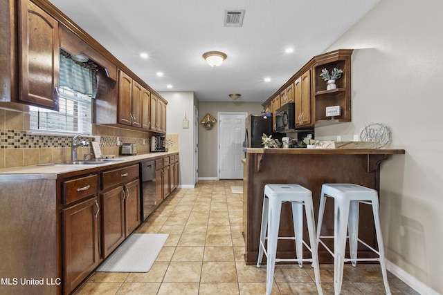 kitchen featuring black appliances, sink, a breakfast bar area, decorative backsplash, and kitchen peninsula