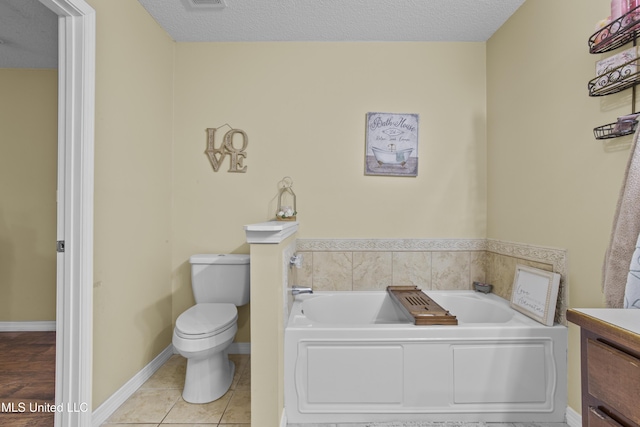 bathroom featuring a tub, tile patterned flooring, vanity, toilet, and a textured ceiling