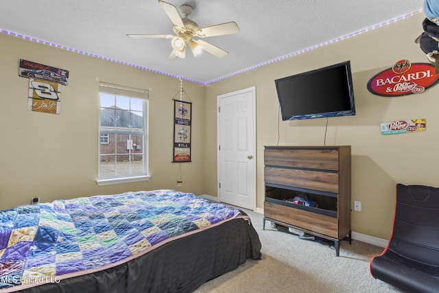 bedroom with ceiling fan, carpet floors, and a textured ceiling