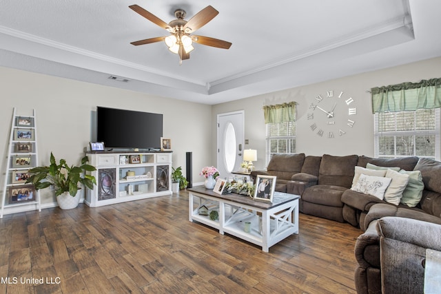 living room with ceiling fan, ornamental molding, dark hardwood / wood-style flooring, and a raised ceiling