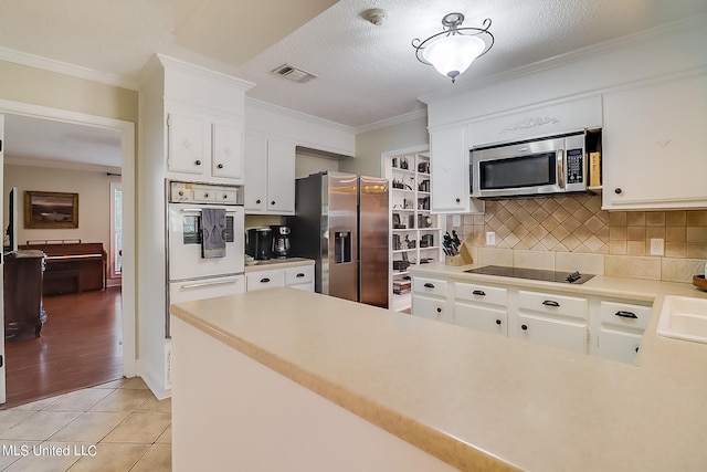 kitchen with crown molding, appliances with stainless steel finishes, white cabinets, and light tile patterned floors