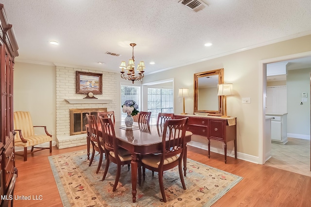 dining space featuring light hardwood / wood-style floors, a textured ceiling, and ornamental molding