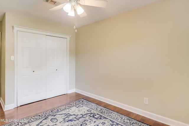 unfurnished bedroom with a closet, wood-type flooring, and ceiling fan