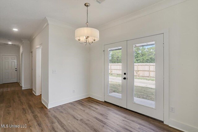 unfurnished dining area featuring french doors, hardwood / wood-style flooring, and crown molding