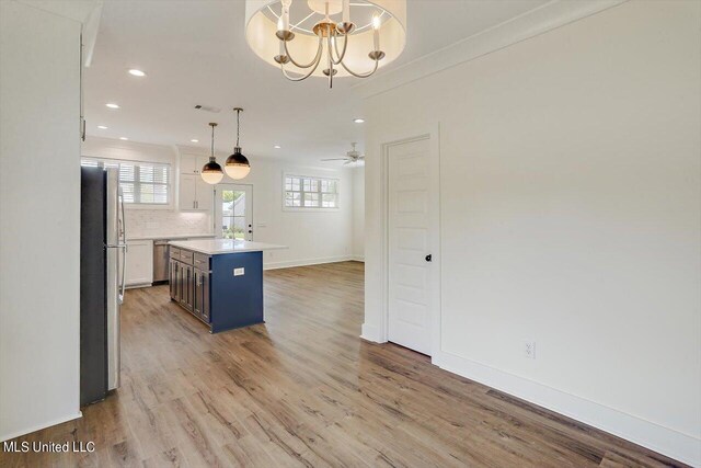 kitchen with a wealth of natural light, decorative light fixtures, a kitchen island, and white cabinets