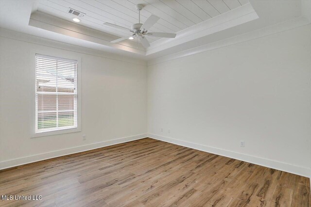 empty room featuring crown molding, ceiling fan, light hardwood / wood-style floors, and a raised ceiling