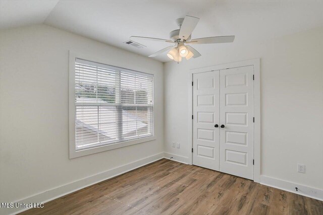 unfurnished bedroom with a closet, ceiling fan, lofted ceiling, and hardwood / wood-style floors