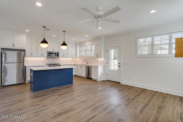 kitchen with a kitchen island, light hardwood / wood-style floors, stainless steel appliances, pendant lighting, and white cabinets