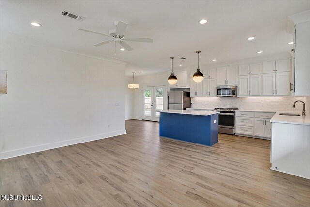 kitchen with a center island, hanging light fixtures, stainless steel appliances, white cabinets, and light hardwood / wood-style flooring