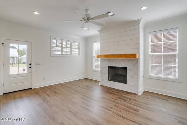 unfurnished living room with light hardwood / wood-style floors, a premium fireplace, and ceiling fan