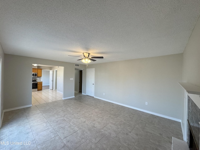 unfurnished living room featuring ceiling fan and a textured ceiling