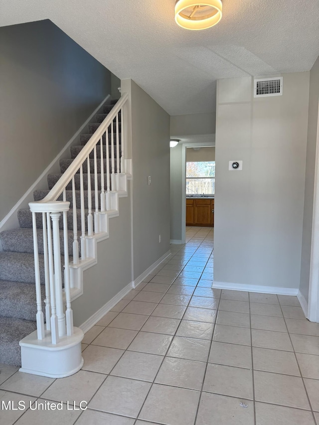 stairway with tile patterned floors and a textured ceiling