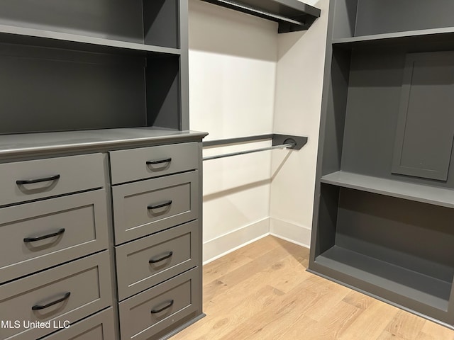 walk in closet with light hardwood / wood-style flooring