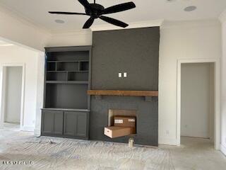 unfurnished living room with built in shelves, ceiling fan, and crown molding