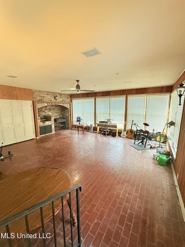 820 Ave Of Pines St, Grenada, MS 38901 - unfurnished living room featuring wooden walls, a fireplace, and a wealth of natural light