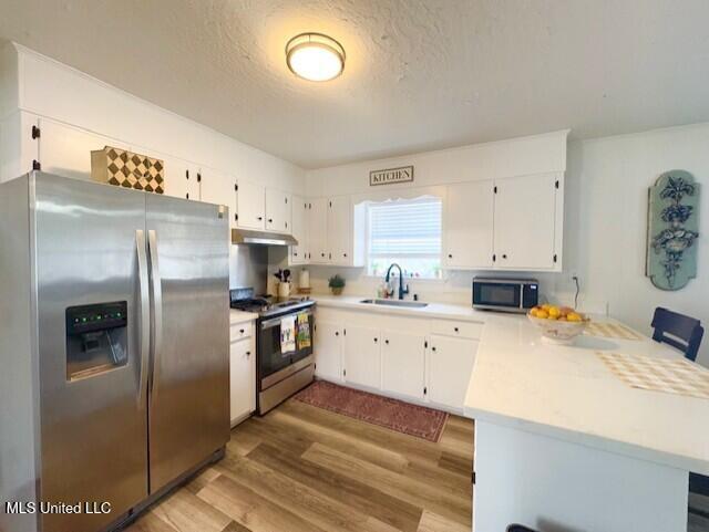 kitchen with sink, white cabinetry, a textured ceiling, appliances with stainless steel finishes, and kitchen peninsula