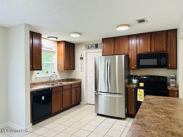 113 Richardson Rd, Picayune, MS 39466 - kitchen featuring black appliances, a sink, light tile patterned floors, a textured ceiling, and baseboards