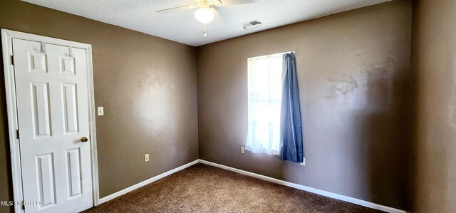 carpeted empty room featuring baseboards, a ceiling fan, and visible vents